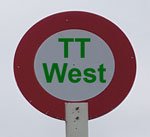 Image of a racecourse winning post with the text "TT West" within the red circle.